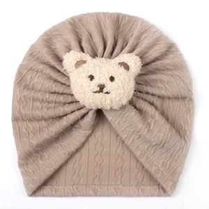 Close-up of khaki knit baby turban hat with a cute beige plush bear ornament