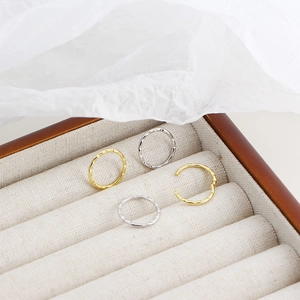 Detail view of gold and silver hammered hoop earrings in a minimalist jewelry box
