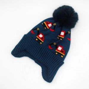 Detail of knit child hat showing excavator jacquard pattern and plush pom-pom