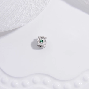 Detailed close-up of a silver barrel bead with green gemstone floral accents for jewelry