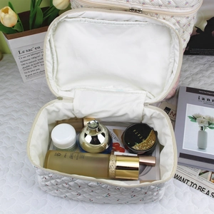 Detailed interior of a white quilted cosmetic bag showing storage capacity and white lining