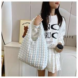 Detail of a large blue and white checkered puffy shoulder bag with a soft quilted texture