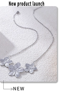 Close-up of silver metal necklace with three floral pendants featuring radial textures
