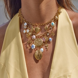 Detail van gelaagde 18K vergulde ketting met hartmedaillon en bloemvormige hangers
