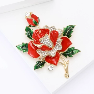 Detailed close-up of a red enamel rose brooch with gold accents and sparkling rhinestones