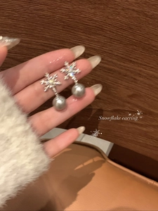 Makroansicht von Schneeflocken-Ohrringen mit Zirkonia und grauem Perlenanhänger