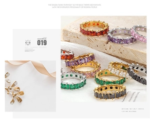 Eternity bands with colorful princess cut stones on textured stone and linen background