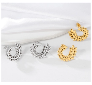Detailed close-up of gold and silver wheat leaf ear studs set on white silk