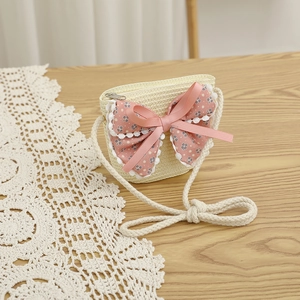 Vue détaillée du sac en paille pour enfant avec nœud floral rose et dentelle sur bois