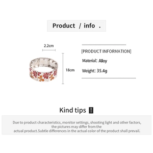Détail des motifs de fleurs en émail coloré sur un large bracelet élastique en alliage