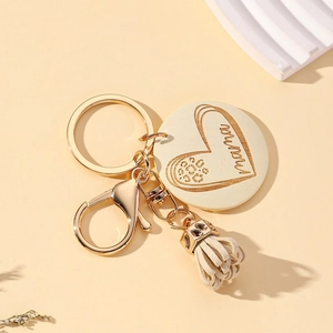 Detail of mama engraved wooden pendant with gold keychain and beige leather tassel