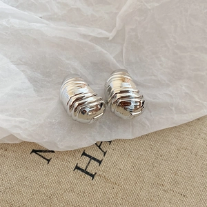 Macro detail of silver croissant hoop earrings with polished textured finish