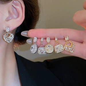 Close-up of heart and square zircon earrings in gold and silver finish on hand