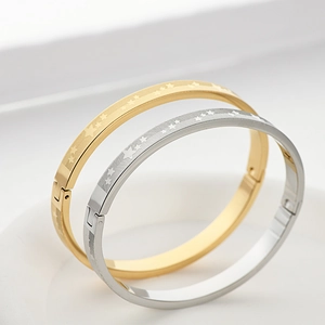 Dettaglio di bracciali in acciaio al titanio oro e argento con motivi a stella su piatto