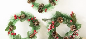 Detailed close-up of Christmas wreath featuring pine needles, cones and red snowy berries