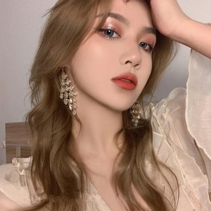 Elegant long crystal tassel drop earrings in gold finish worn by a female model