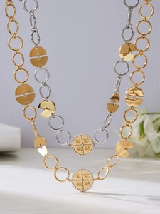 Detailed view of layered gold and silver IC XC NIKA medallion necklaces with zircon