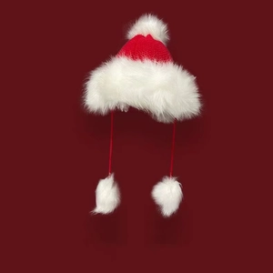 Close-up of festive red knit hat with plush white pom-poms and soft faux fur lining