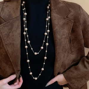 Double-layer gold chain necklace featuring mixed-size champagne pearls on a brown suit blazer