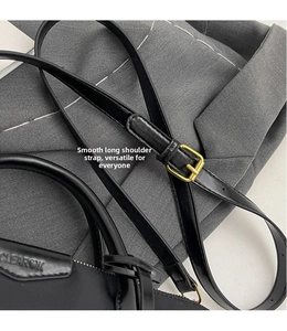 Detail of adjustable black leather strap with gold buckle on a nylon tote bag