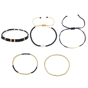 Fünfteiliges Armband-Set in Schwarz und Gold mit Kleeblatt-Anhänger auf weißem Hintergrund