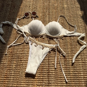 Detail of white shell bikini with ocean charms and pearls on a woven straw mat