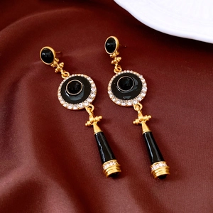 Detail of vintage gold and black enamel drop earrings with rhinestones on silk