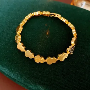 Gold gourd link bracelet with polished and hammered texture on green velvet display