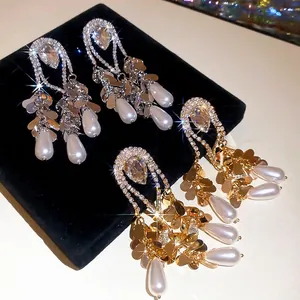 Luxury gold and silver fringe earrings with crystals and pearl drops on a black stand