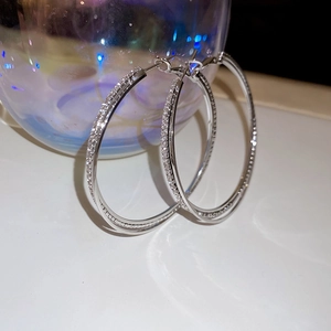 Macro shot of silver paved diamond hoop earrings with a shiny interwoven double-layer design