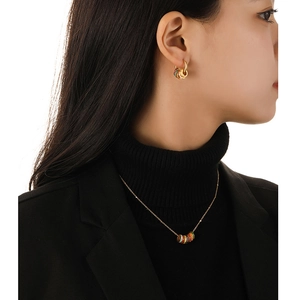 Vintage matte gold necklace and earrings set with colorful enamel rings on black background