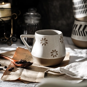 Minimalist white ceramic mug with embossed brown floral pattern and rustic speckled glaze