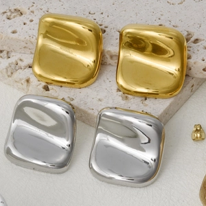Polished gold and silver square stud earrings displayed on a textured grey stone base