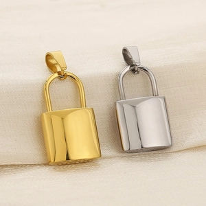 Close-up of polished gold and silver padlock charms on soft beige fabric background