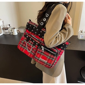 Detail of red plaid tote bag featuring metal chains, rivets and double zipper pockets