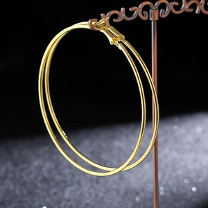 Detail view of large gold hoop earrings hanging on a vintage metal jewelry stand
