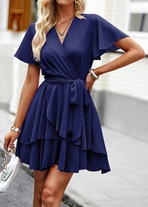 Détail d'une robe bleue marine à col en V avec taille à lacets et ourlet à volants étagés