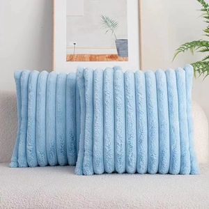 Detail of two light blue faux fur throw pillows with soft striped texture on a sofa