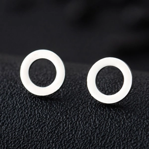 Macro shot of minimalist silver geometric round stud earrings on a dark textured surface