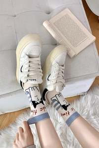 Detail of cute cartoon cat pattern socks paired with white chunky platform sneakers