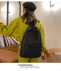 Close-up of durable black nylon backpack with top handle and front zipper pocket detail