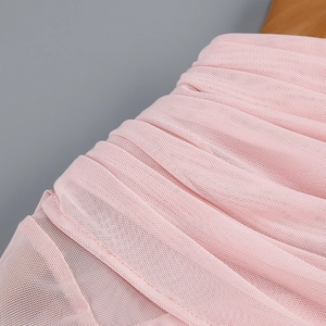 Détail du tissu en maille rose montrant des plis fins et la texture froncée de la robe