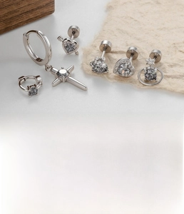 Close-up of punk style titanium steel earrings set with grey zircon stones and heart charms