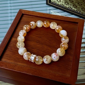 Detail of yellow natural stone beads with a gold-tone crystal charm on a wooden box
