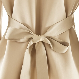 Detailed view of a beige satin belt tied in a bow on the back of a stylish dress