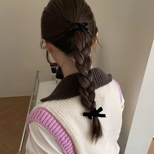 Elegant black velvet bow hair clip worn on a braided hairstyle for a vintage look