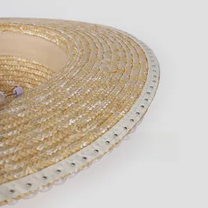 Close-up of straw sun hat brim with elegant pearl bead accents and woven trim