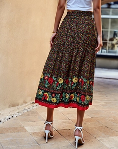 Détail du motif floral sur une jupe midi noire avec taille élastique et bordure rouge