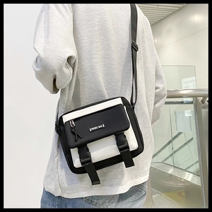 Detail view of the black and white messenger bag with buckle straps and logo plaque