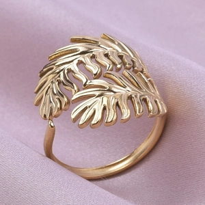 Macro shot of gold leaf stainless steel ring detail on elegant silk fabric background